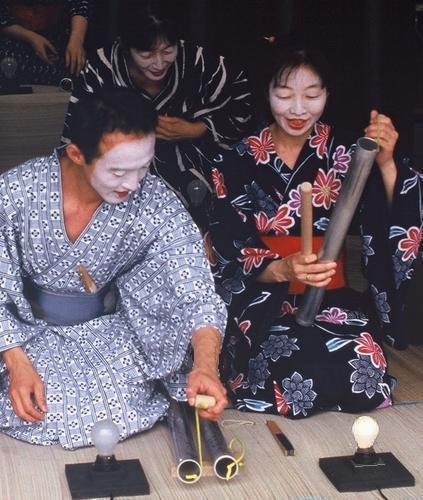 three Japanese ladies gazing at a light bulb